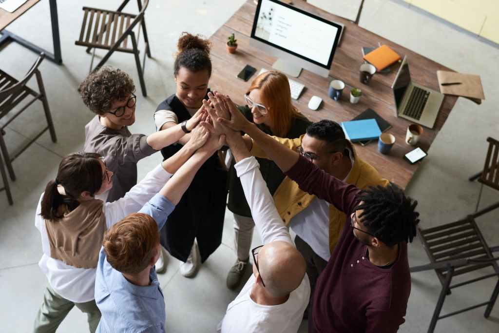 Group of diverse individuals forming a huddle touching their hands in the middle as a team.